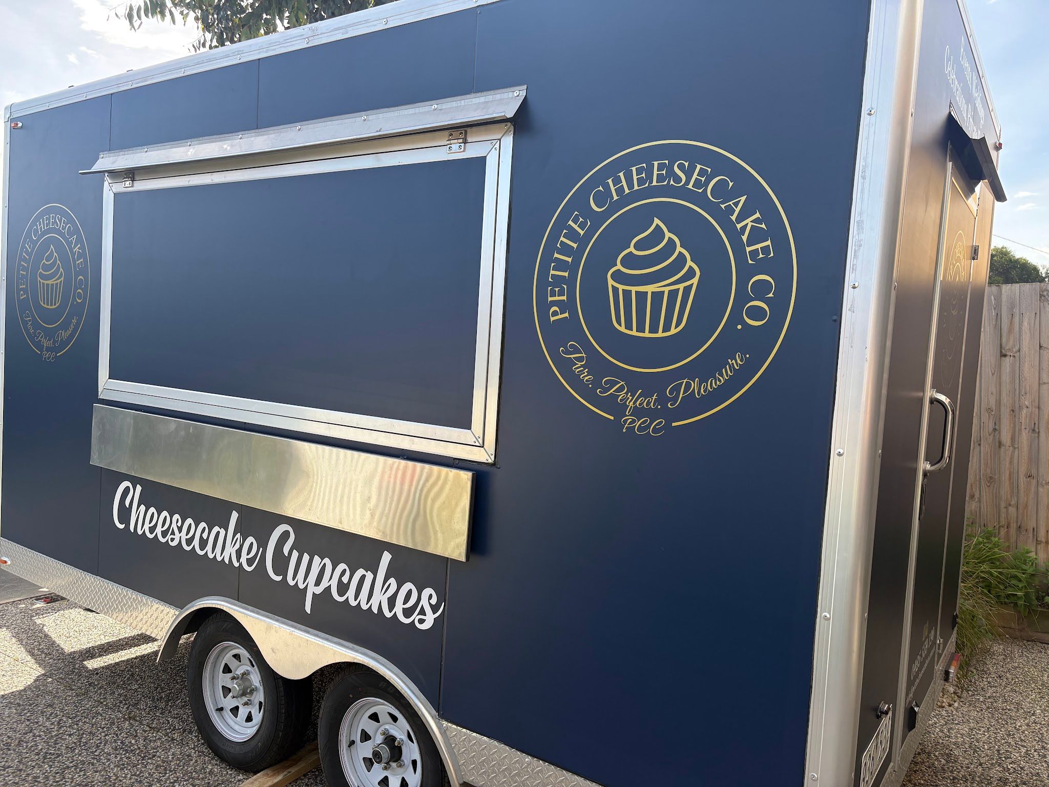 Petite Cheesecake Co navy food trailer with gold branding and 'Cheesecake Cupcakes' script, photographed outdoors